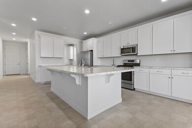 Kitchen featuring appliances with stainless steel finishes, white cabinetry, recessed lighting, light countertops, and a kitchen breakfast bar