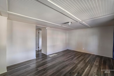Spare room with dark wood-style floors and baseboards