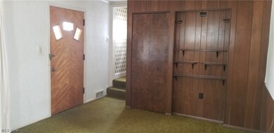 Carpeted entryway with wood walls