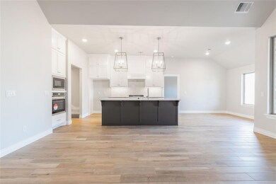 Kitchen with a sink, black microwave, visible vent