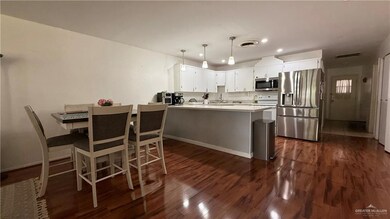 Kitchen featuring stainless steel appliances, a peninsula, dark wood-style flooring, recessed lighting, and hanging light fixtures