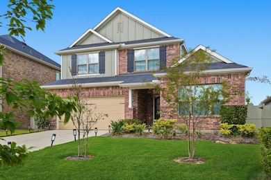 This two-story home features a traditional brick facade, a neatly manicured lawn, and a two-car garage. It offers a welcoming front entrance with shrubs and trees for added curb appeal.