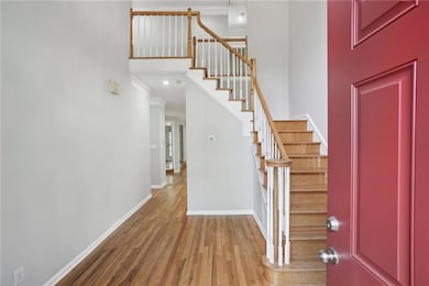 Entrance foyer with ornamental molding, wood finished floors, baseboards, stairway, and a high ceiling