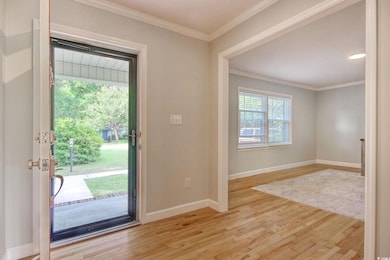 Entrance foyer with wood finished floors, baseboards, and ornamental molding