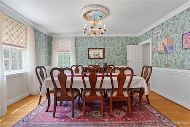 Dining room with wallpapered walls, a chandelier,