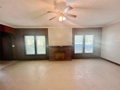 Living room with tile patterned floors, plenty of natural light, a fireplace, a textured ceiling, and ceiling fan