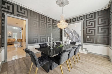 This elegant dining room features a modern design with a striking VERSACE wallpaper and a sophisticated chandelier.