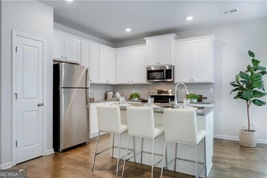 Kitchen with stainless steel appliances, wood finished floors, backsplash, an island with sink, and recessed lighting