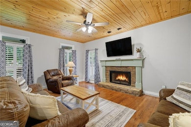 Upgraded living room featuring hardwoods, wood-burning gin fireplace, and stunning wood ceiling to accentuate the balance between rustic and craftsman charm.