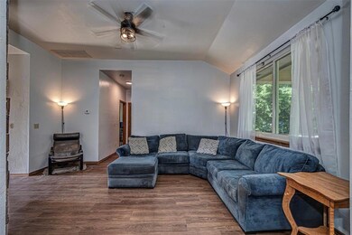 Living area featuring ceiling fan, vaulted ceiling, and wood-style flooring
