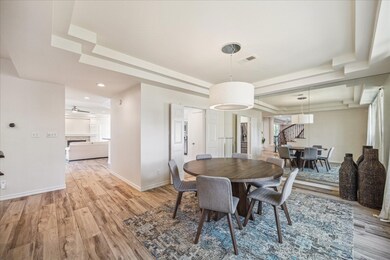 GRAND FORMAL DINING FEATURES A MODERN CHANDELIER,