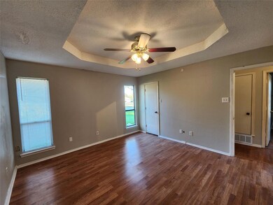 Unfurnished room with ceiling fan, a raised ceiling, and wood-type flooring