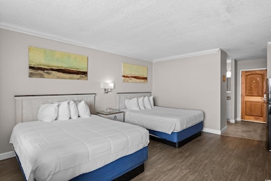 Bedroom featuring dark wood-type flooring, a textured ceiling, and crown molding