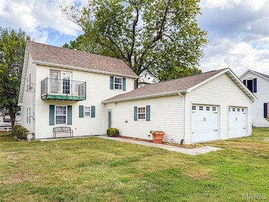 View of front of property featuring a front yard, a balcony, and roof with shingles