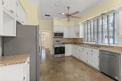 Kitchen featuring stainless steel appliances, ornamental molding, a ceiling fan, healthy amount of natural light, and backsplash