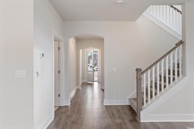 Foyer entrance featuring arched walkways, wood finished floors, and stairway