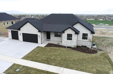 View of front of home featuring stone siding, covered porch, a garage, concrete driveway, and a front yard