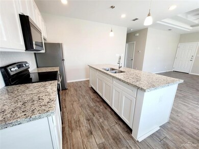 Kitchen featuring white cabinetry, a sink, stainless steel microwave, and wood finished floors