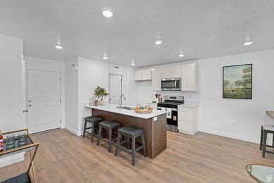 Kitchen with a kitchen breakfast bar, a peninsula, white cabinets, stainless steel appliances, and light wood-style floors