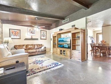 Living area featuring beam ceiling, finished conc