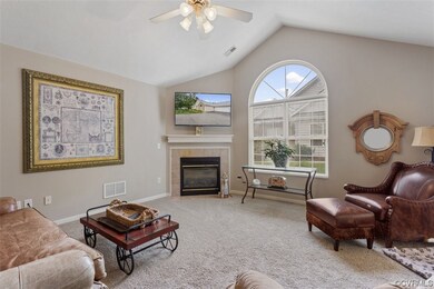 Carpeted living room with a fireplace, ceiling fan