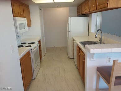 Kitchen with white appliances, brown cabinets, and tile countertops
