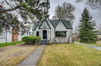 Tudor house with a front lawn, a chimney, stucco s