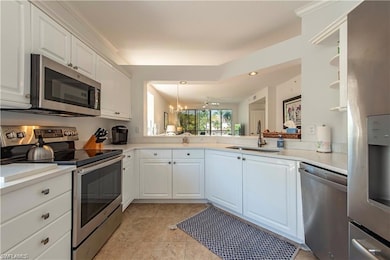 Kitchen with white cabinets, appliances with stain