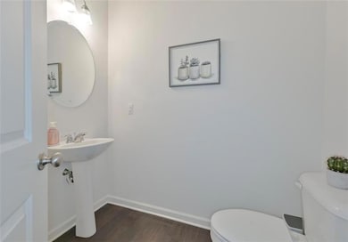 Bathroom featuring toilet, wood finished floors, and baseboards