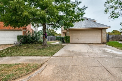 View of property hidden behind natural elements featuring brick siding, a garage, concrete driveway, and a shingled roof