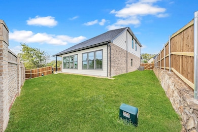 Rear view of house with a fenced backyard, brick siding, and roof with shingles