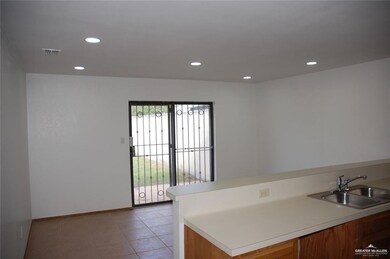 Kitchen with a peninsula, light countertops, recessed lighting, light tile patterned floors, and brown cabinetry