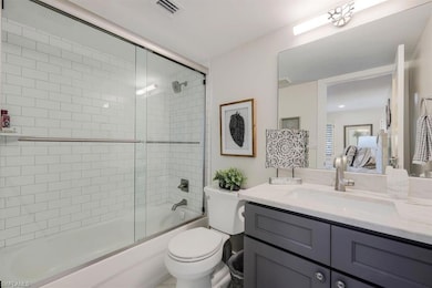 Bathroom with vanity and bath / shower combo with glass door