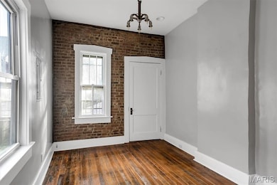 Spare room with brick wall and dark wood-style flooring