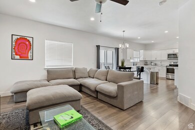Living room with recessed lighting, ceiling fan, light wood-style flooring, and a chandelier