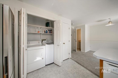 Laundry area with separate washer and dryer, light colored carpet, and light flooring