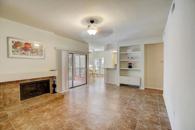Unfurnished living room featuring a textured ceiling, a fireplace, ceiling fan, light tile patterned flooring, and built in shelves