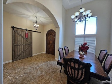 Dining room featuring a chandelier, arched walkways, inlaid floor details, tile patterned flooring, and a barn door