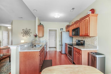 Kitchen with stainless steel appliances, backsplash, wood finished floors, and a peninsula