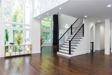Foyer with a towering ceiling, wood finished floors, recessed lighting, and stairs