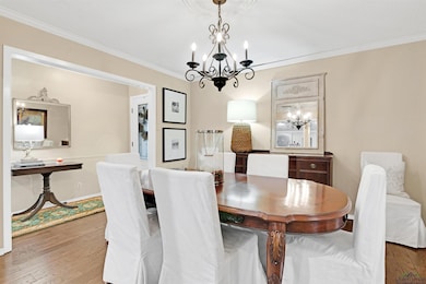 Dining area with hardwood / wood-style flooring, ornamental molding, and a chandelier