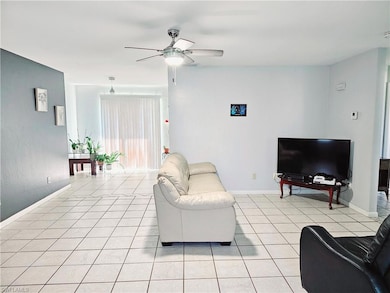 Living area featuring a ceiling fan, light tile patterned floors, and baseboards