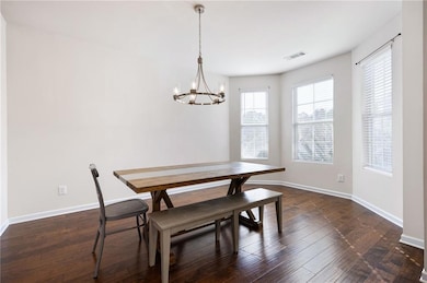 Dining area featuring dark wood-type flooring and a chandelier