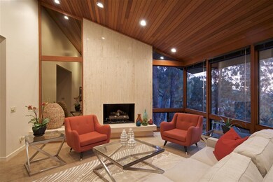 A travertine fireplace and vaulted wood ceiling ad