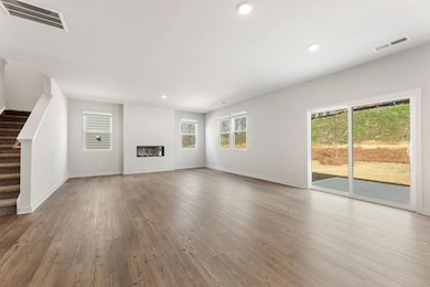 Unfurnished living room featuring stairs, wood finished floors, baseboards, and recessed lighting