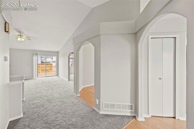 Hallway with light colored carpet and lofted ceili