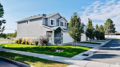 View of front facade with stucco siding, stone siding, a garage, driveway, and roof with shingles