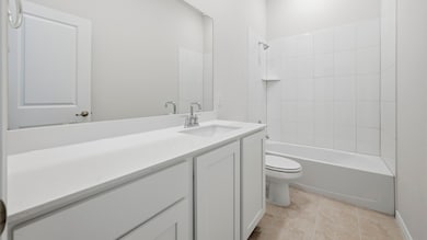 Bathroom with vanity, shower / bathtub combination, and light tile patterned flooring