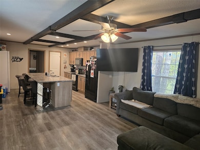 Living area with beam ceiling, dark wood-type flooring, and a ceiling fan