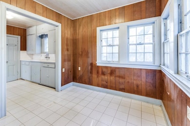 Kitchen featuring baseboards, wood walls, light c